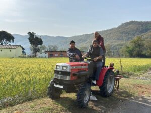 Three elderly gentlemen posing on a red tractor at The Corbett Rajae Homestay.