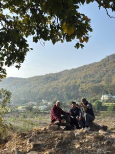 Three senior friends sitting on rocks overlooking the Corbett landscape.
