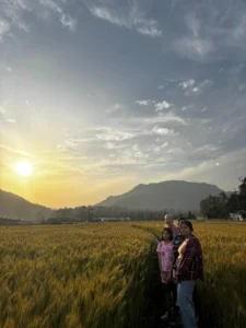A family standing in a golden wheat field during sunset near Jim Corbett National Park, Uttarakhand.